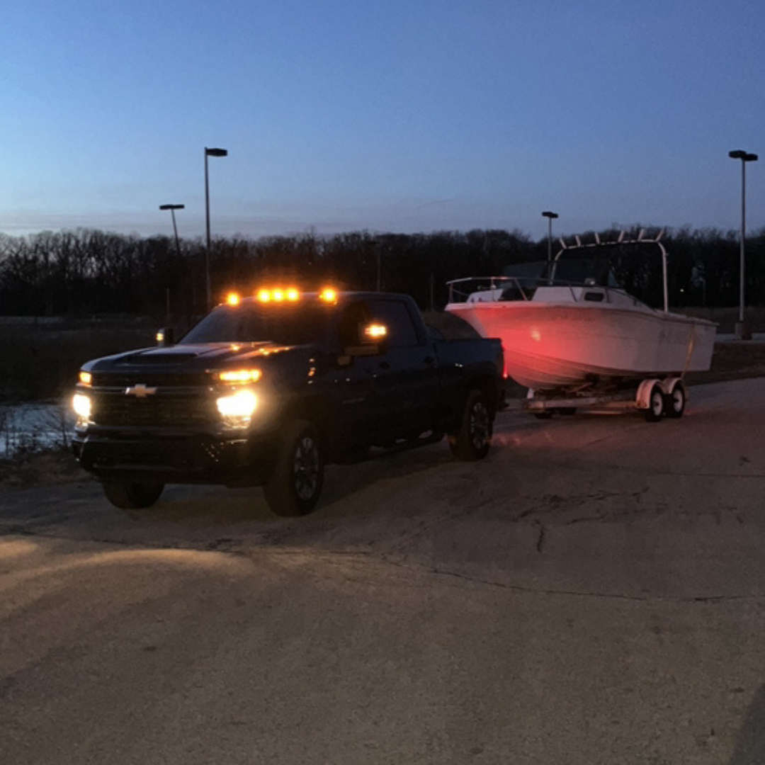Boat junk removal at night by Patriot Clean Out, hauling away storm-damaged boat from a parking lot in Northwest Indiana.